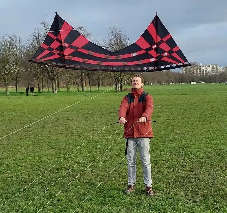 Alban Kites devant un cerf-volant KQK rouge et noir piloté au dogstake