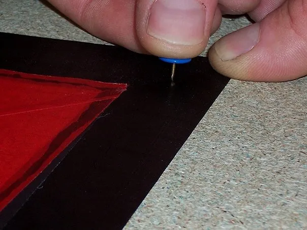 Fixing a wing with tacks. (Holes are no problem, as this 3 cm black outline will be folded twice to make a 1 cm black hem/contour all around the sail).
